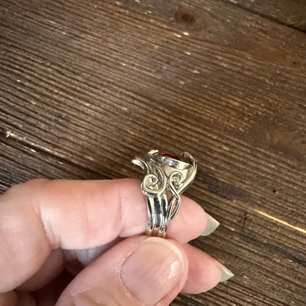 Ring in silver metal intricate with teardrop shaped amber color stone